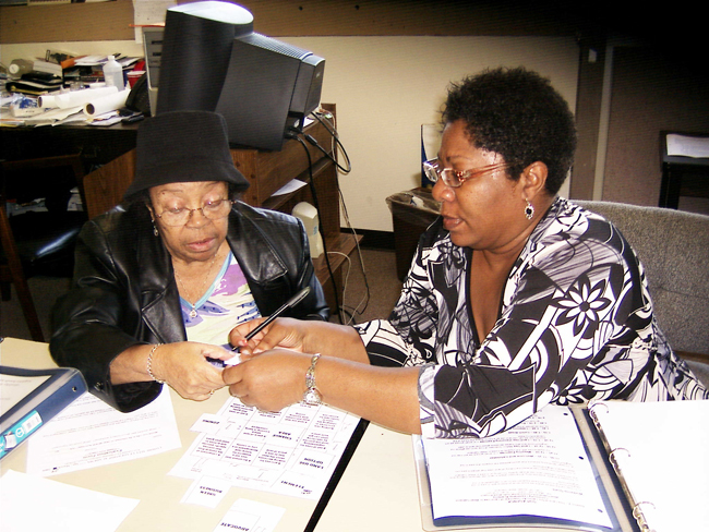 Volunteer Cassandra Martin trains a senior neighbor about air quality as they pour over several notebooks.