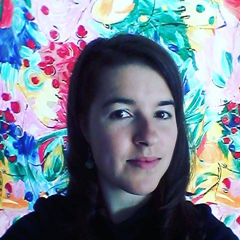 Close-up of Meg loking straight at the camera in a dark shirt against a multi-color floral background.