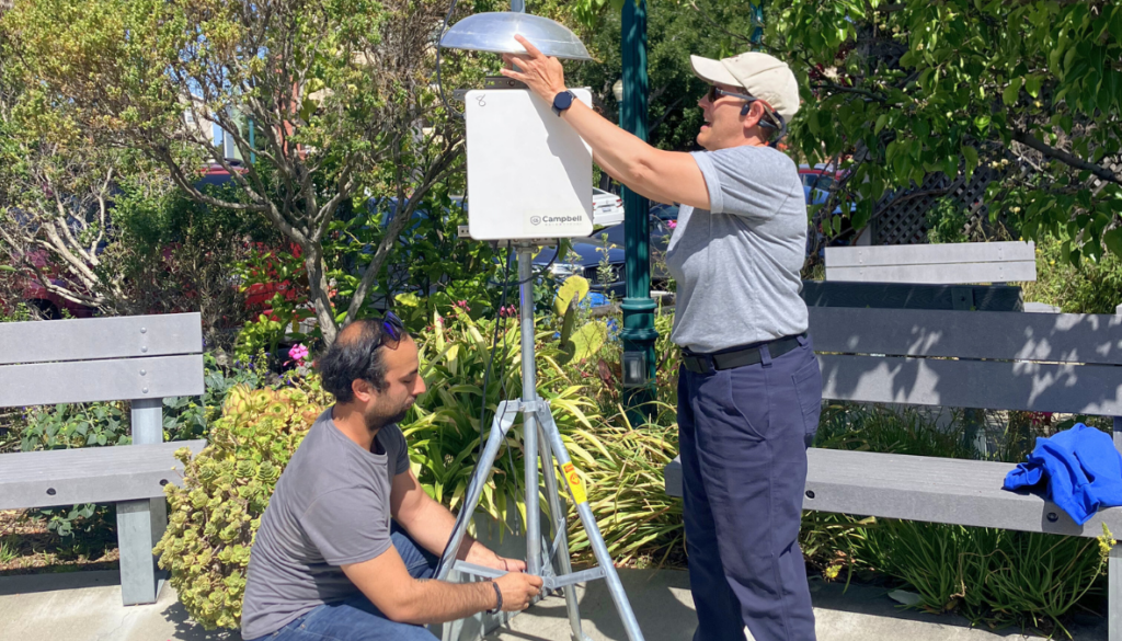 Two people set up an air monitor