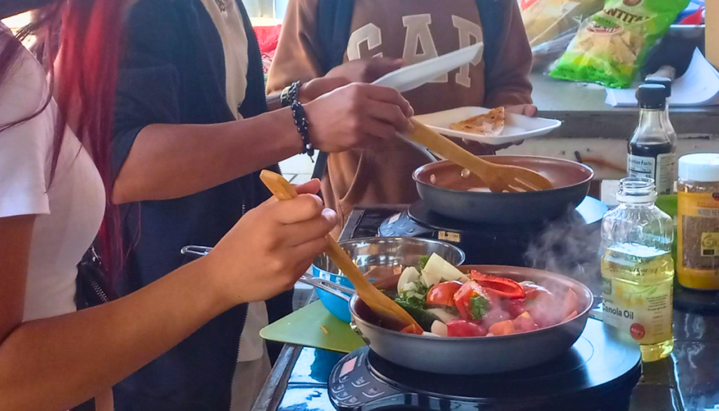 Students stir fresh veggies on electric induction cooktops