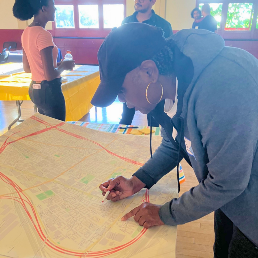 A person bends over a map pf West Oakland, marking it with a sharpie