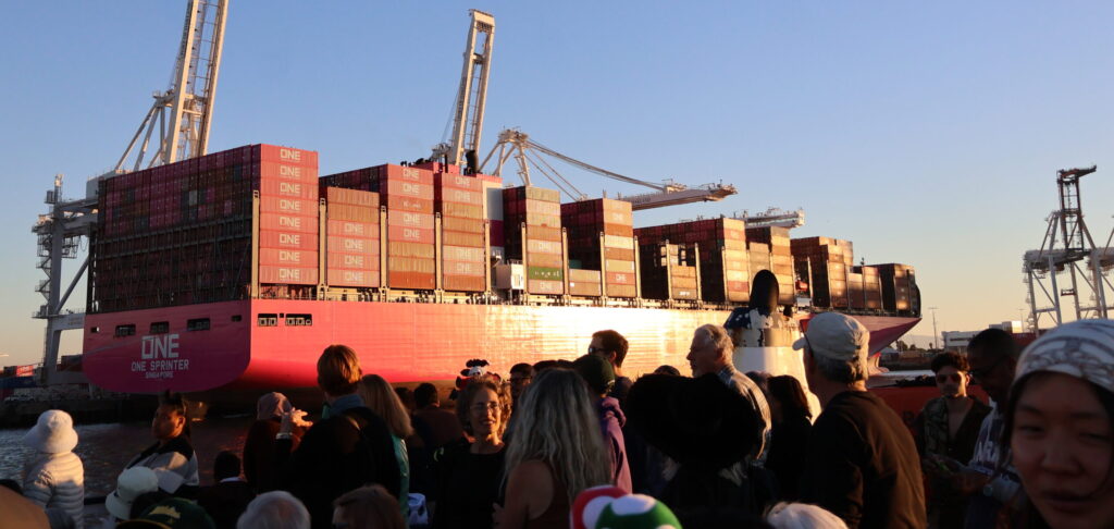 People gathered in front of a container ship