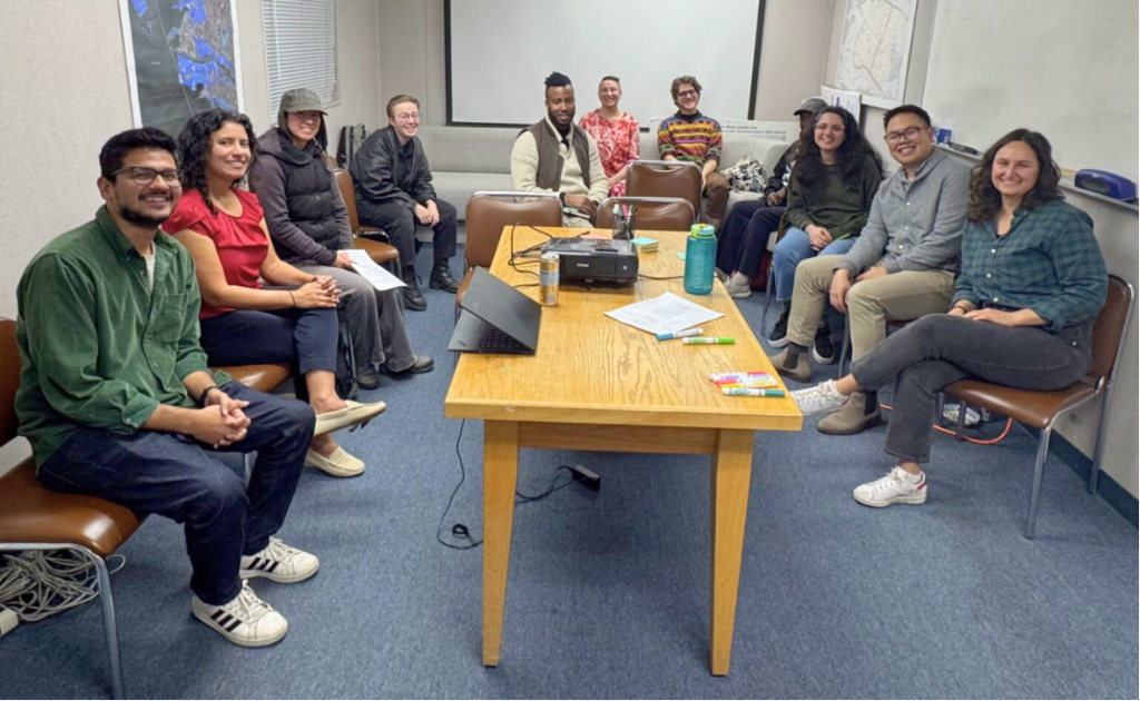 A group of people sit in the
WOEIP office around a table and projector